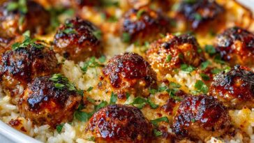 Baked honey garlic meatballs over rice in a casserole dish, garnished with green onions.