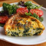 Crustless quiche with cottage cheese and spinach baked in a pie dish, sliced and garnished with herbs.