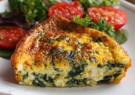 Crustless quiche with cottage cheese and spinach baked in a pie dish, sliced and garnished with herbs.
