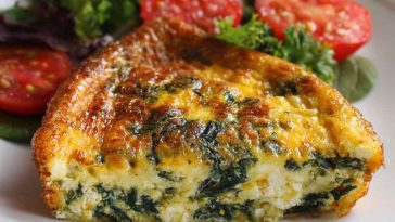 Crustless quiche with cottage cheese and spinach baked in a pie dish, sliced and garnished with herbs.