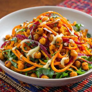 Colorful Moroccan carrot and chickpea salad with herbs and citrus dressing in a rustic bowl.