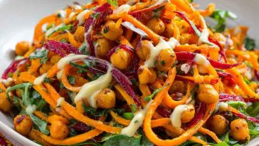 Colorful Moroccan carrot and chickpea salad with herbs and citrus dressing in a rustic bowl.