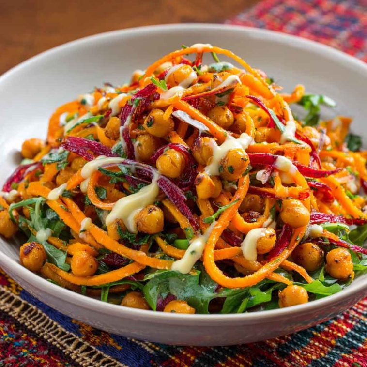 Colorful Moroccan carrot and chickpea salad with herbs and citrus dressing in a rustic bowl.
