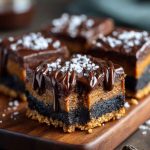 A tray of chocolate cheesecake bars with a chocolate cookie crust, creamy cheesecake layer, and glossy chocolate ganache topping, cut into perfect squares.