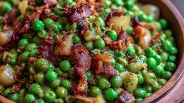A serving dish of Thanksgiving peas with pear slices and crispy pancetta, garnished with fresh thyme and a drizzle of olive oil.