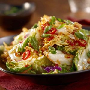 Salad Frito Cowboy Cabbage with shredded cabbage, ground beef, tomatoes, cheese, and crunchy Fritos, tossed in a zesty dressing and served in a large bowl.