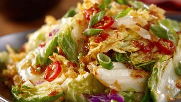 Salad Frito Cowboy Cabbage with shredded cabbage, ground beef, tomatoes, cheese, and crunchy Fritos, tossed in a zesty dressing and served in a large bowl.