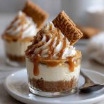Mini cookie butter cheesecake cups layered with crushed speculoos cookies, creamy cheesecake filling, and a drizzle of cookie butter, served in clear dessert cups.