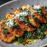 Golden crispy chicken cutlets served over romaine lettuce with Caesar dressing, Parmesan shavings, and lemon wedges.