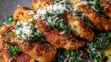 Golden crispy chicken cutlets served over romaine lettuce with Caesar dressing, Parmesan shavings, and lemon wedges.