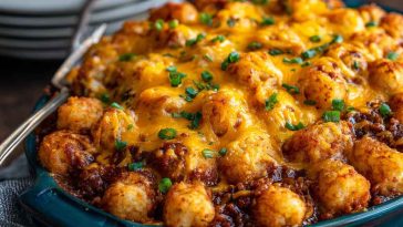 Golden tater tots layered over hearty chili and melted cheese, baked in a casserole dish and garnished with green onions.