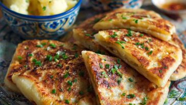 Golden-browned potato farls served on a breakfast plate with butter, eggs, and grilled tomatoes.