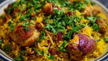 Fragrant Persian-style chicken pilaf with golden basmati rice, tender chicken pieces, saffron threads, and garnished with barberries and fresh herbs.