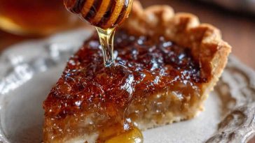 A golden slice of burnt honey pie with a caramelized top and flaky crust, served on a ceramic plate with a drizzle of honey and a sprig of thyme.