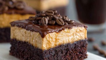 A decadent tray of frosted coffee brownies with glossy mocha frosting, cut into squares and garnished with chocolate shavings and espresso beans.