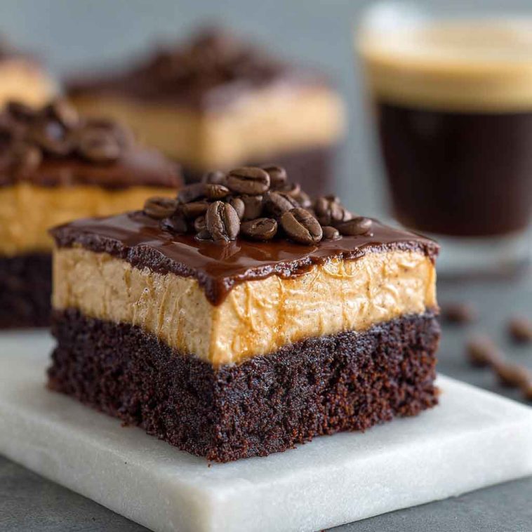 A decadent tray of frosted coffee brownies with glossy mocha frosting, cut into squares and garnished with chocolate shavings and espresso beans.