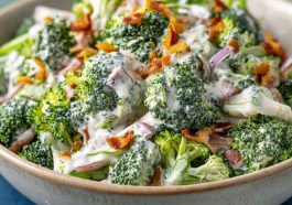 Creamy broccoli ranch salad with bacon, cheddar, and sunflower seeds in a white bowl.