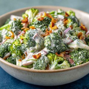 Creamy broccoli ranch salad with bacon, cheddar, and sunflower seeds in a white bowl.