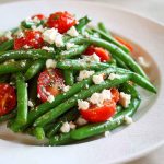 Golden baked parmesan-crusted chicken breasts with a crispy breadcrumb and cheese coating, garnished with parsley and served with lemon wedges.