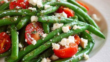 Golden baked parmesan-crusted chicken breasts with a crispy breadcrumb and cheese coating, garnished with parsley and served with lemon wedges.