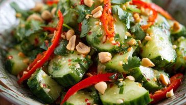 A vibrant bowl of spicy peanut cucumber salad with sliced cucumbers, chopped peanuts, chili flakes, and fresh cilantro.