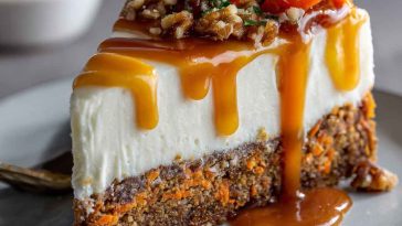 Layered carrot cake cheesecake topped with smooth cream cheese frosting and garnished with chopped walnuts and cinnamon.