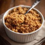 Golden graham cracker crumble topping sprinkled over a dessert, with visible buttery crumbs and hints of cinnamon.