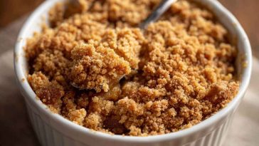 Golden graham cracker crumble topping sprinkled over a dessert, with visible buttery crumbs and hints of cinnamon.