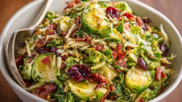 A vibrant chopped salad with shaved Brussels sprouts, cherry tomatoes, salami, mozzarella, olives, and Italian dressing, served in a rustic bowl.