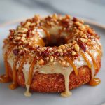 Maple-glazed donuts stacked on a cooling rack with drips of glaze and a sprinkle of cinnamon.