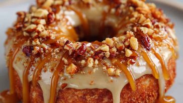 Maple-glazed donuts stacked on a cooling rack with drips of glaze and a sprinkle of cinnamon.