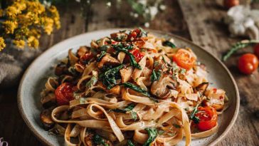 A colorful bowl of vegan pasta tossed with roasted vegetables, fresh herbs, and a creamy dairy-free sauce.