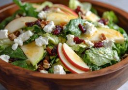 Honeycrisp apple and feta salad with mixed greens, cranberries, and walnuts in a white bowl.