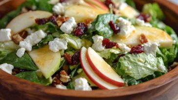 Honeycrisp apple and feta salad with mixed greens, cranberries, and walnuts in a white bowl.