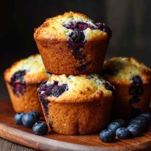 Freshly baked blueberry cottage cheese muffins on a cooling rack, with golden tops and juicy blueberries peeking through.