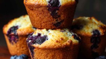 Freshly baked blueberry cottage cheese muffins on a cooling rack, with golden tops and juicy blueberries peeking through.