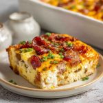 A golden-baked breakfast casserole filled with eggs, cheese, bacon, and hash browns, garnished with fresh herbs.