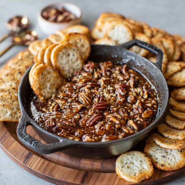 Creamy no bake pecan pie dip topped with caramel drizzle and chopped pecans, served with graham crackers.