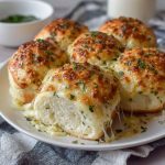 Golden cheesy garlic rolls baked fresh, oozing melted cheese and brushed with garlic butter, served warm on a tray.