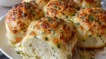 Golden cheesy garlic rolls baked fresh, oozing melted cheese and brushed with garlic butter, served warm on a tray.