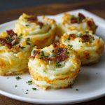 Golden mashed potato nests baked until crispy on the outside, filled with creamy cheese and savory toppings, garnished with fresh herbs.