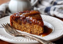 Moist Amish applesauce cake topped with glaze and sprinkled with cinnamon on a rustic serving plate.