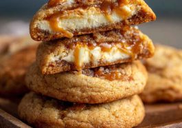 Salted caramel cheesecake cookies with golden caramel drizzle and creamy centers on a baking tray.