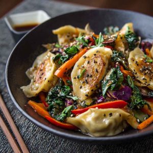 Potsticker stir fry with vegetables and sesame seeds in a skillet