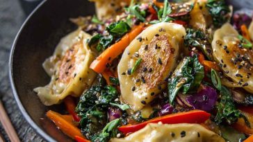 Potsticker stir fry with vegetables and sesame seeds in a skillet