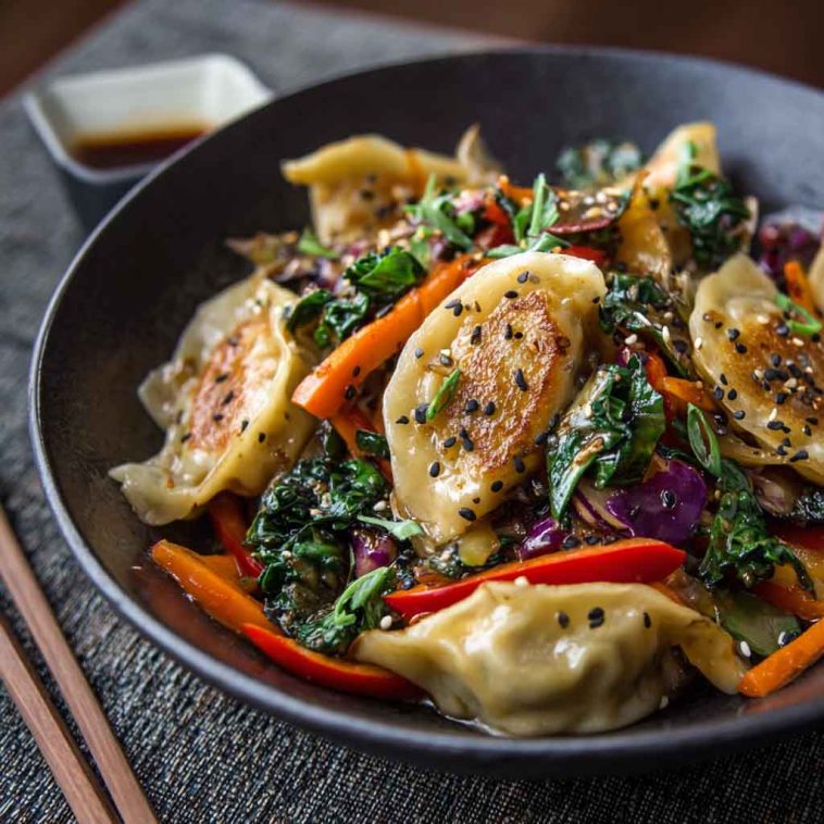 Potsticker stir fry with vegetables and sesame seeds in a skillet