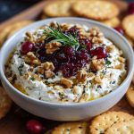 Creamy whipped feta dip topped with cranberries and walnuts, served in a rustic bowl with crackers.