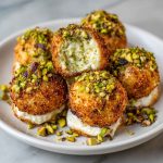 Elegant ricotta pistachio honey bites topped with crushed pistachios and drizzled with golden honey, served on a rustic platter.