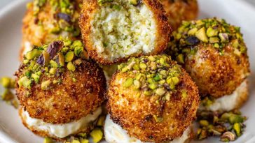Elegant ricotta pistachio honey bites topped with crushed pistachios and drizzled with golden honey, served on a rustic platter.