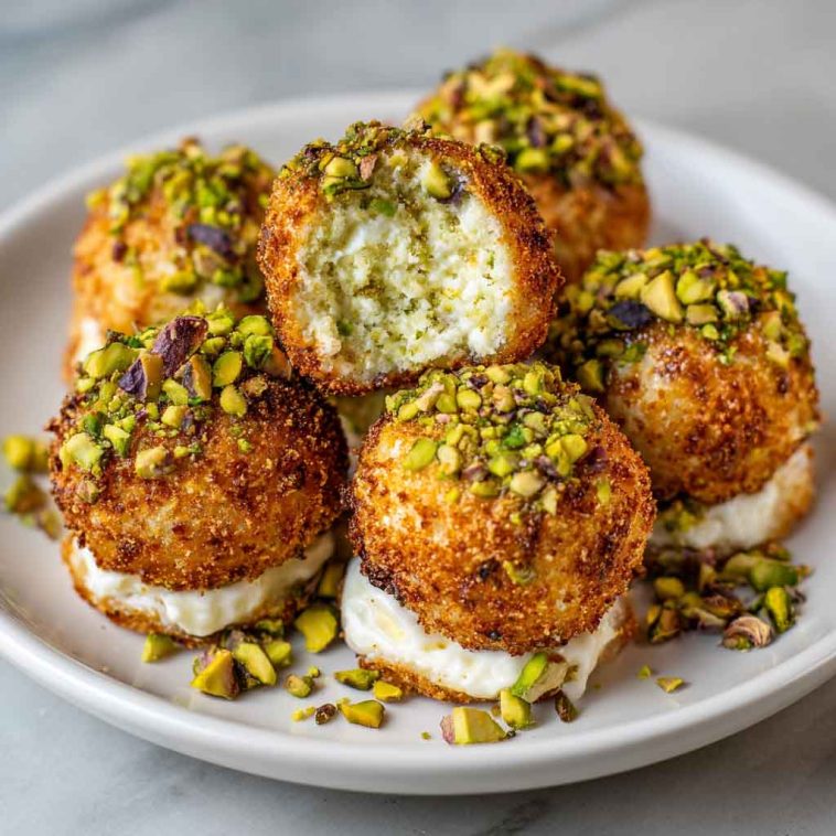 Elegant ricotta pistachio honey bites topped with crushed pistachios and drizzled with golden honey, served on a rustic platter.
